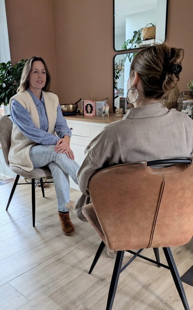 2 mensen zitten op een stoel en praten samen.